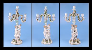 Three continental porcelain figural three-armed candelabra with encrusted flower decoration, 52cms