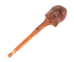 A folk art treen tobacco pipe, the bowl carved in the form of a mans head, 14cms long.