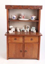 An oak doll's house dresser, 23cms wide; together with a group of doll's house ceramics, mostly