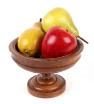 A 19th century turned walnut bowl with three painted wooden fruit, 16cms diameter.