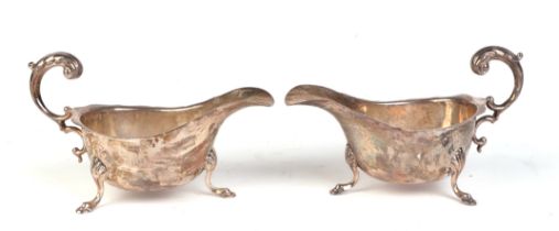 A pair of George V silver sauce boats with scroll handles and shell capped hoof feet, Birmingham