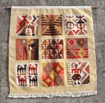 An African woven wall hanging decorated with stylised people and animals, on a beige ground, 95 by