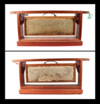 Two mahogany cased bee honeycomb displays, each 61cms wide; together with some honey making