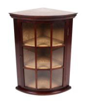 A reproduction mahogany wall mounted bowfronted corner cupboard, the glazed panelled door