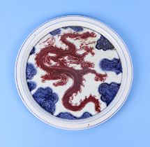 A Chinese blue, red & white plate decorated with a dragon amongst clouds, 30cm diameter. Condition