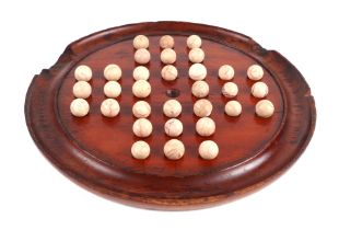 A mahogany solitaire board, with a selection of marbles, 28cm diameter.