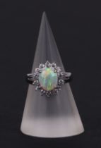 A platinum ring, set with an oval opal cabochon, within a halo of diamonds, opal approx 1.05ct,
