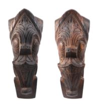 A pair of oceanic hardwood carved corbels, depicting stylised faces, 47cm high.