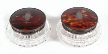 A pair of George V glass cosmetic jars with tortoiseshell and silver lids, each 11cm wide (2)