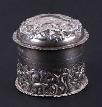 A Victorian silver box and cover of cylindrical form, decorated a cherub and foliate scrolls. London