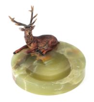 An early 20th century cold painted bronze figure of a red deer, on a green onyx ashtray base, 12cm