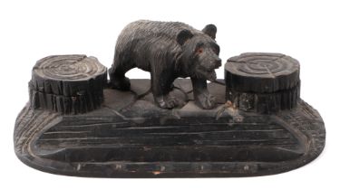 A Black Forest carved wood pen and ink stand, having a bear flanked by two ink wells and pen dish,
