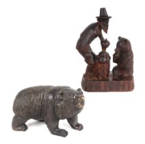 A Black Forest figural group depicting a bear and a man, 15cms wide; together with a similar