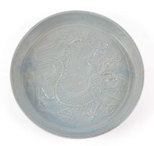 A Chinese celadon glazed shallow dish, decorated in relief a dragon amongst clouds, 20cm diameter,