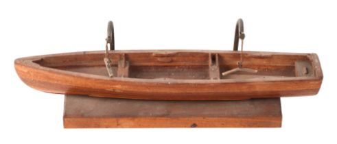 A teak scale model of a rowing boat, 30cm long, mounted on a brass and wooden stand.