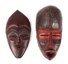 An African Tribal carved hardwood mask, with traces of red paint, 52cm high, together with another