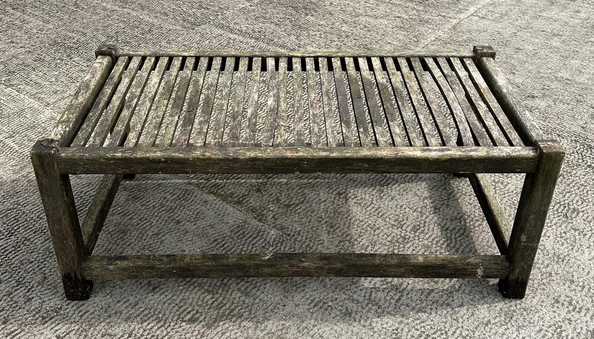 A well weathered teak garden coffee table, 98cm wide. Condition Report There are two slats which are