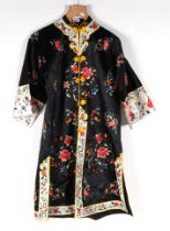 A Chinese silk embroidered robe decorated with scrolling flowers, on a black ground.