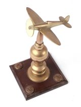 A trench art cast brass model of a Spitfire, mounted on a brass and Bakelite plinth, wingspan 11cm.