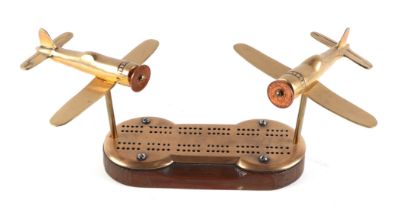 A pair of trench art cast brass models Wild Cat aircrafts, mounted on a cribbage board, 34cm wide.