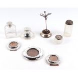 A silver capstan ink well, a group of silver miniature photo frames, a silver hat pin stand and