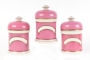 Three Victorian pink pottery apothecary jars and covers, with gilt band decoration, each approx 15cm