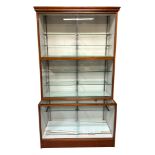 A large glazed shop display cabinet, having an upper section with two tiers, with fitted shelves,