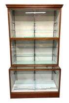 A large glazed shop display cabinet, having an upper section with two tiers, with fitted shelves,