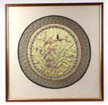 A Chinese oval silk embroidered panel, depicting a bird in flowering foliage, framed and glazed,