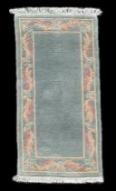 A Chinese rug, with pale green ground, and floral boarder, 142 by 68cm.