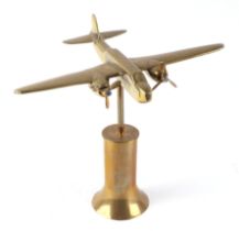 A trench art cast brass model of twin engine aircraft, mounted on a brass plinth, wingspan 26cm.