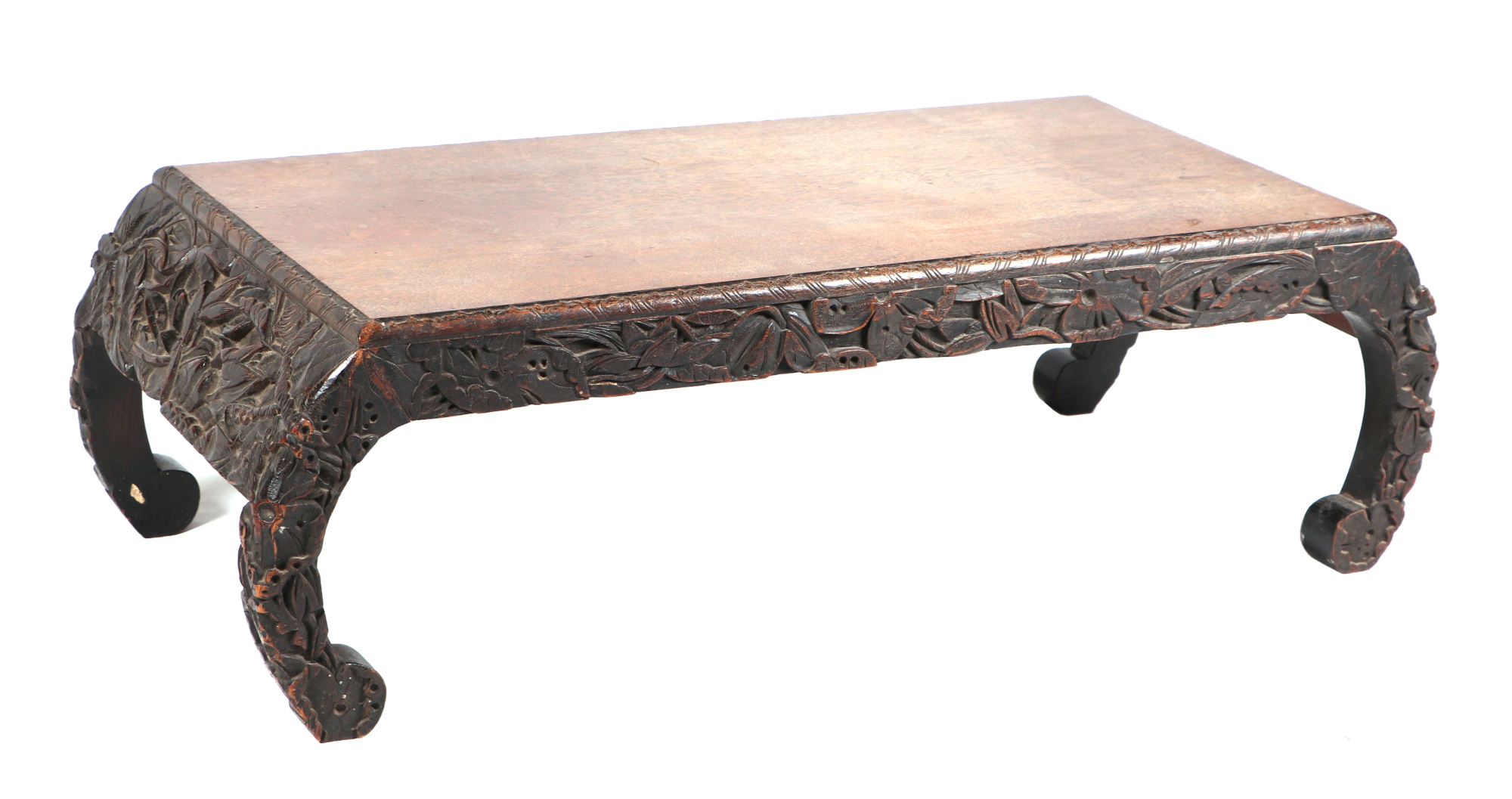 A Burmese low table, the frieze and scroll legs profusely carved decoration, 104cm wide.