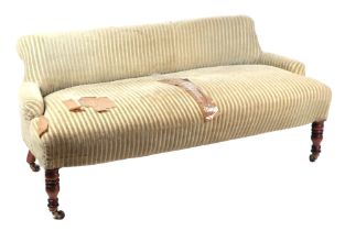 A 19th century upholstered low backed settee on walnut legs terminating in brass castors.