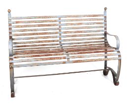 A well weathered painted iron strap work garden bench, with scroll arms and feet, and ball