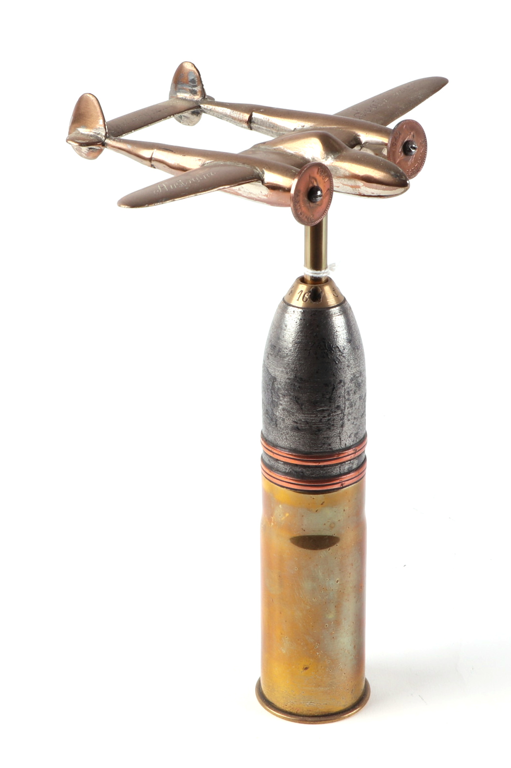 A trench art cast brass model of a Lockheed P-38 Lighting, mounted on a shell case, wingspan 16cm.