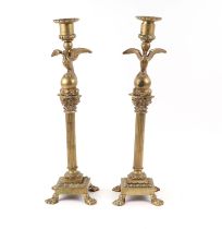 A pair of French brass Empire style candlesticks with eagle perched on bull sconces, Corinthian