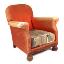 A 1920s upholstered open armchair, on oak bun feet.