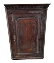 A George III oak hanging corner cabinet, having a panelled door enclosing shelves, 83cm wide.
