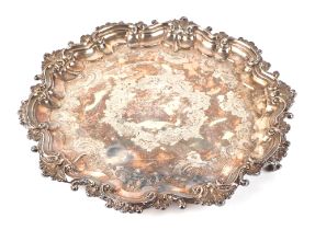 An Edwardian silver salver, of shaped circular form, with engraving decoration standing on three