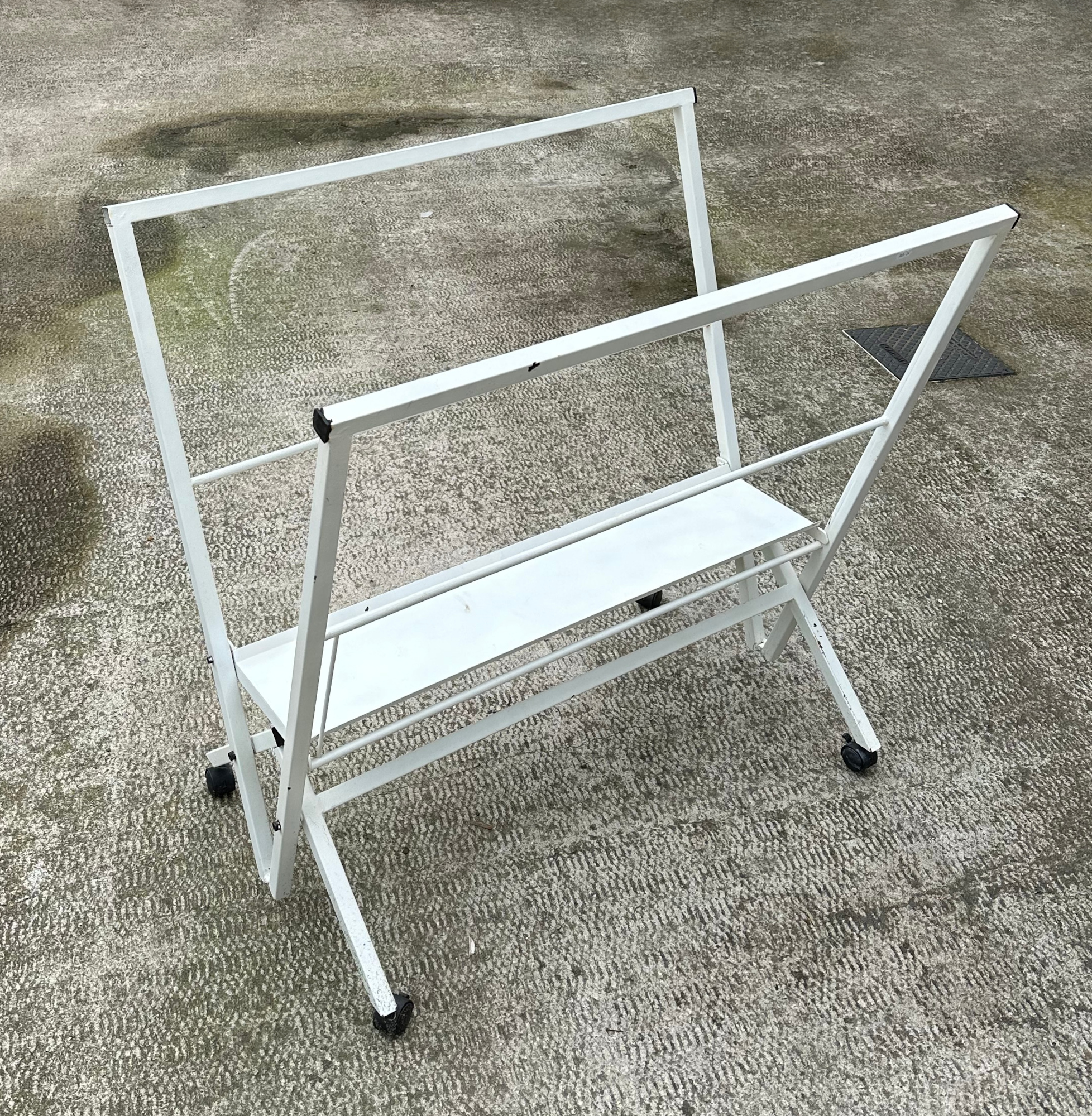 A white painted metal folio/poster stand, 102cm wide.