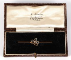 An Edwardian yellow metal bar brooch, set with three aquamarine and a single seed pearl, 5.5cm wide,