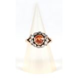 An 18ct gold diamond cluster ring, set with a large central orange stone (possibly Citrine),