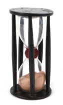 An early 18th / late 19th century hourglass within a treen cage, 18cm high.