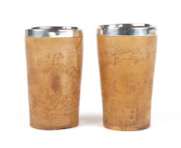 A pair of 19th century carved horn beakers, depicting fox hunting scenes and having silver