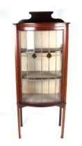An Edwardian mahogany bowfront display cabinet, the leaded glass panelled door enclosing a shelved