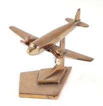 A trench art cast brass model of a DC3 Decoata aircraft, mounted on a brass plinth, wingspan 15cm.