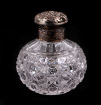 A white metal topped cut glass scent bottle of globular form, 11cm high.