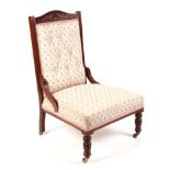 A late Victorian/Edwardian carved walnut upholstered nursing chair, with turned front legs.