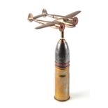 A trench art cast brass model of a Lockheed P-38 Lighting, mounted on a shell case, wingspan 16cm.