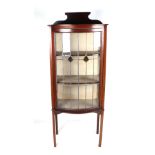 An Edwardian mahogany bowfront display cabinet, the leaded glass panelled door enclosing a shelved
